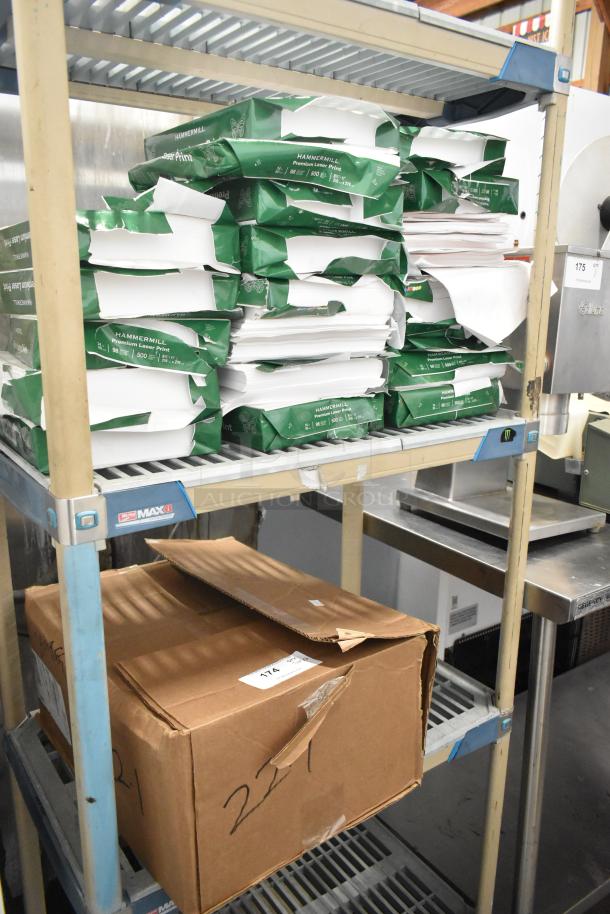 Two-tier lot with multiple reams of Hammermill paper and a cardboard box on a metal shelf. Reams are stacked, some with torn packaging.