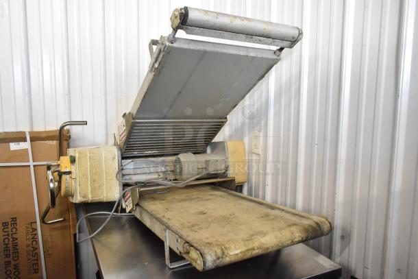 Rondo Seewer metal commercial reversible dough sheeter, floor style, missing legs, showing visible wear, ideal for bakery use.