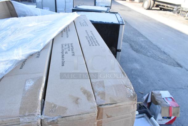 Boxes containing new scratch and dent items, partially wrapped in plastic, with labels showing specifications and origins.