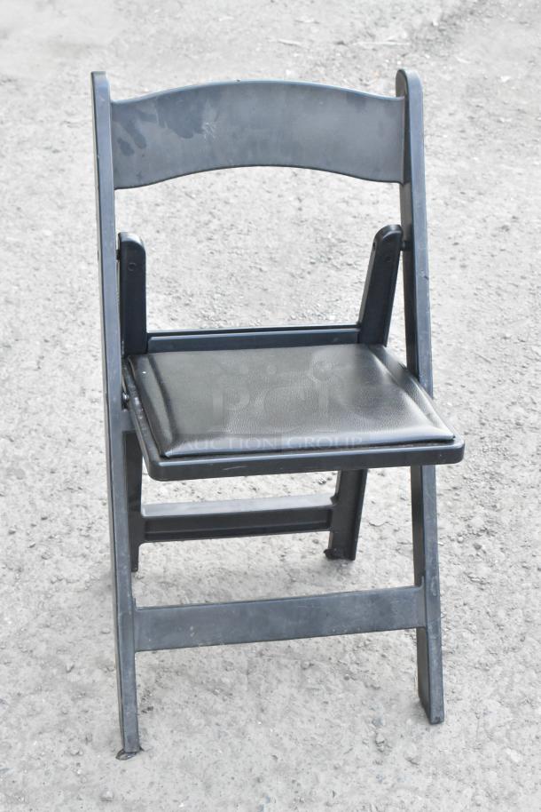 Black folding banquet chair, metal frame with vinyl seat, shows signs of wear. Part of 106-item auction lot.