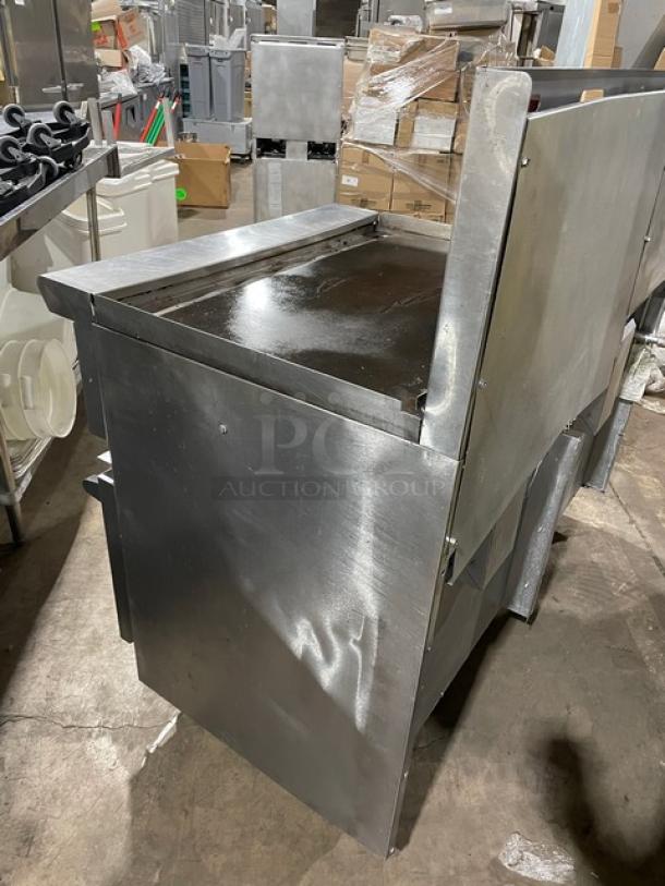 American Range commercial stainless steel gas-powered 4-burner range. Includes raised flat griddle, split top, double oven, broiler/cheese melter, backsplash, and wired oven rack. On legs, used condition.
