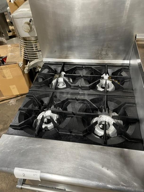 American Range commercial stainless steel 4-burner gas range with flat griddle top, double oven, broiler, and backsplash.