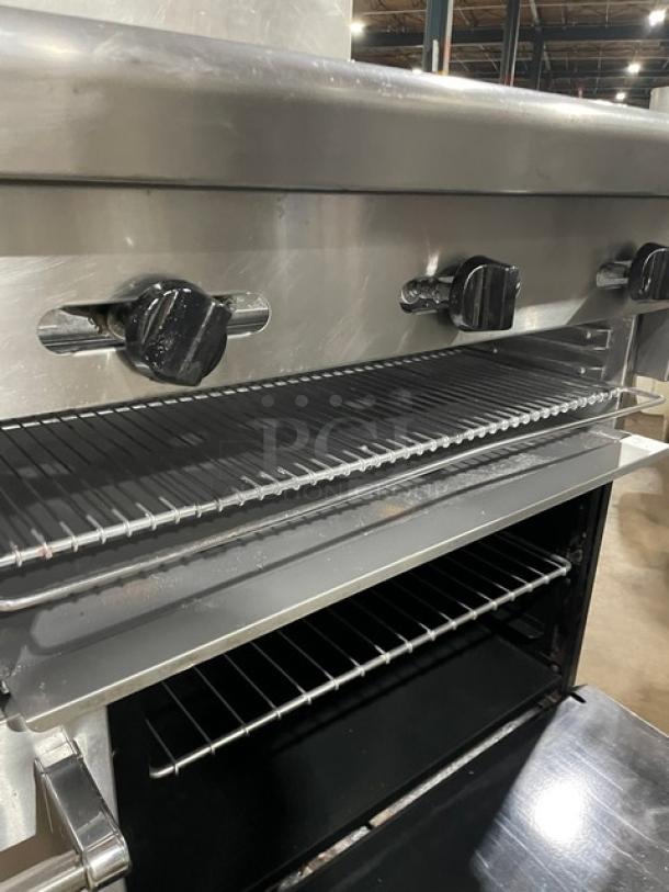 American Range Commercial stainless steel 4-burner gas range with raised flat-griddle, double oven, broiler, and backsplash.