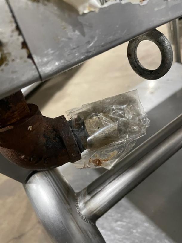Stainless steel connector on the WoodStone commercial griddle, secured with tape, showing signs of wear.