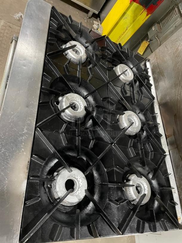 Vulcan commercial stainless steel 6-burner gas range with overhead salamander, wired oven rack, and backsplash, on legs.