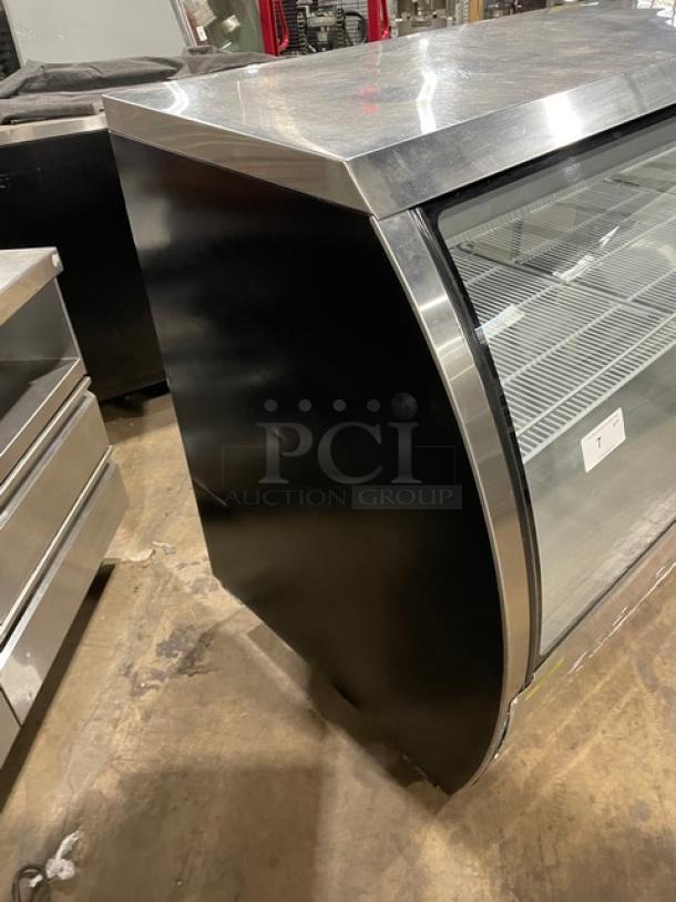 Alamo XDC200 stainless steel deli display with curved glass, poly-coated rack, rear glass doors. Minor wear visible.