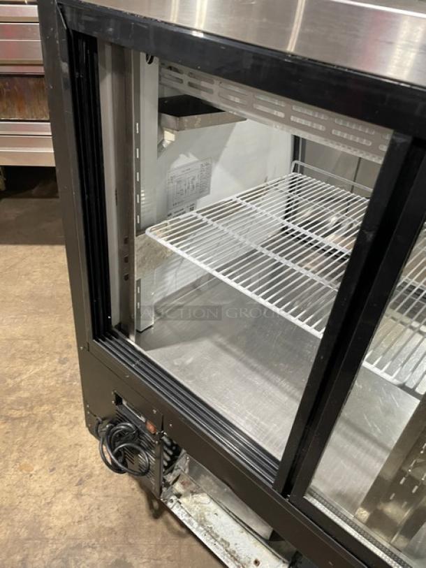 Alamo XDC200 stainless steel deli display showcase with curved glass, poly-coated wire rack, and rear sliding glass doors.