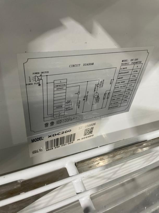 Alamo XDC200 stainless steel deli display showcase, curved glass, rear sliding doors, model and serial labels visible, 110V.