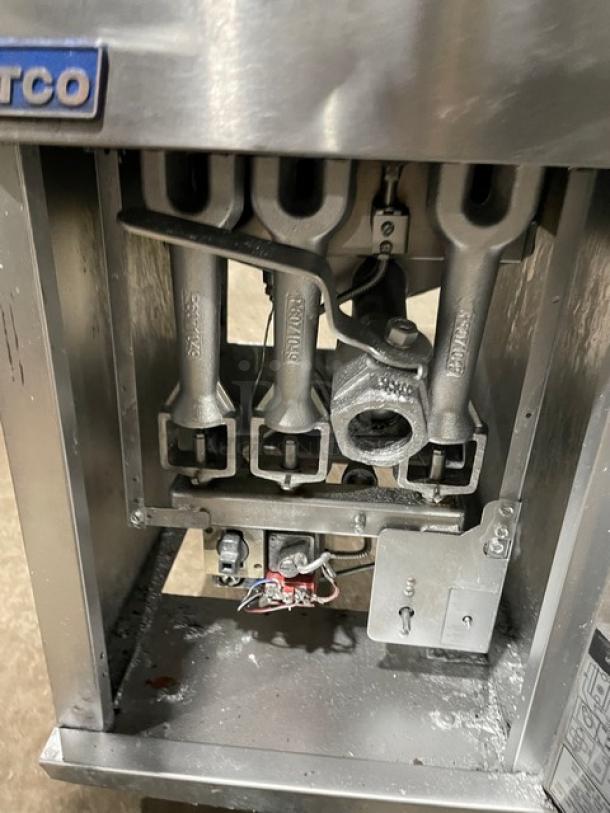Pitco commercial stainless steel natural gas deep fat fryer with backsplash, basket hanger, and casters. Visible components include gas burners.
