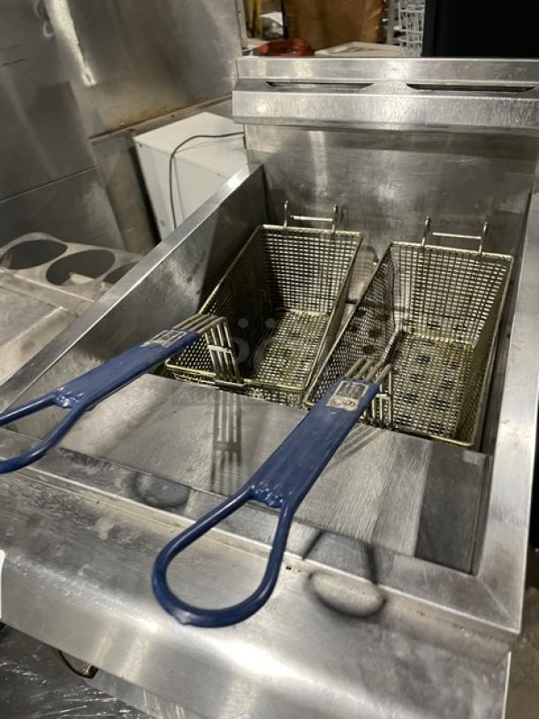 CPG commercial stainless steel natural gas countertop deep fat fryer with back splash, basket hanger, and fry basket on legs.