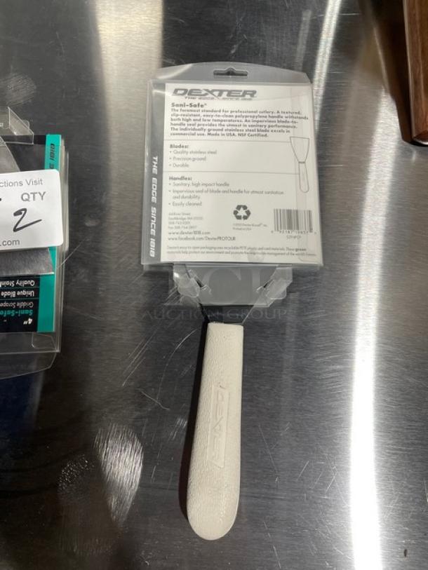 Brand new Dexter Russell Sani-Safe stainless steel 4" griddle scraper, model S294, with white grip handle in packaging.