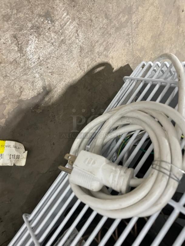 Coiled white power cord on top of a poly-coated wired rack from Accucold Pharma-Vac ARS6PV refrigerator.