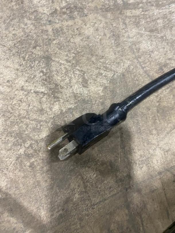 Close-up of a black power plug on a textured surface, likely part of a Winco EFS16 electric countertop fryer.