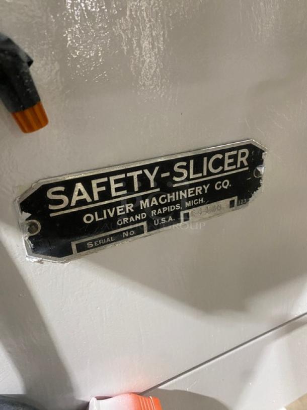Oliver Safety-Slicer commercial bread slicing machine, white, with stainless steel worktop, serial number 86430, on legs.