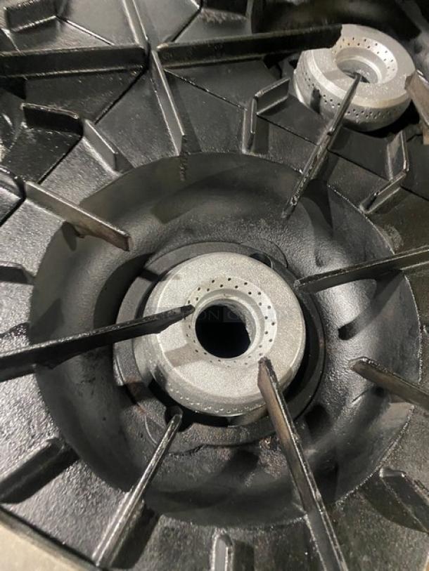 Close-up view of Vulcan commercial range burner, showing clean cast-iron grates and central gas opening.