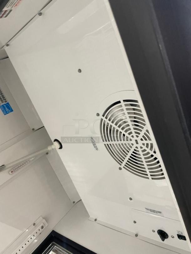 True Commercial GEM-23 refrigerator interior, showing the black single glass swing door, poly coated wired rack, Energy Star label, and fan.