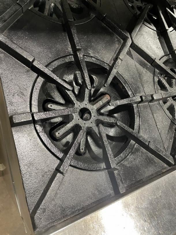 Garland stainless steel 6-burner range/oven combo with backsplash, overhead salamander shelf, and wired oven rack on casters.