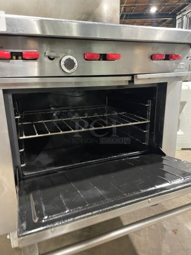 Garland commercial stainless steel 6-burner range/oven combo with backsplash, overhead salamander shelf, and wired oven rack. On casters.