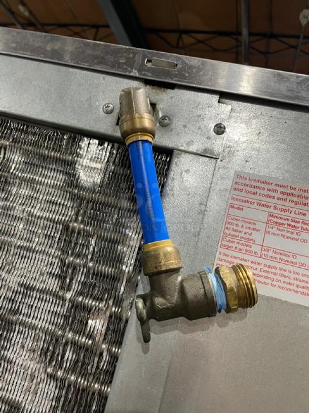 Hoshizaki KM-515MAH ice machine detail showing blue water line and valve. Includes manufacturer label with installation guidelines.