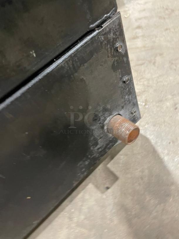 Commercial countertop char broiler, stainless steel, natural gas powered, with cast iron grate, visible wear on surface.