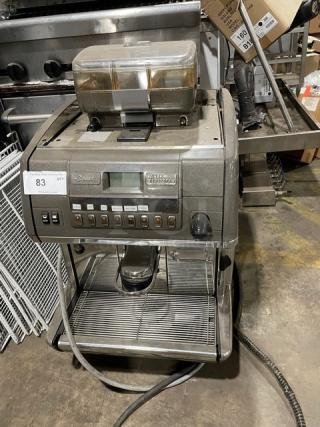 LaCimbali commercial automatic espresso machine with stainless steel steam wand, drip tray, and clear bean hopper, on legs.