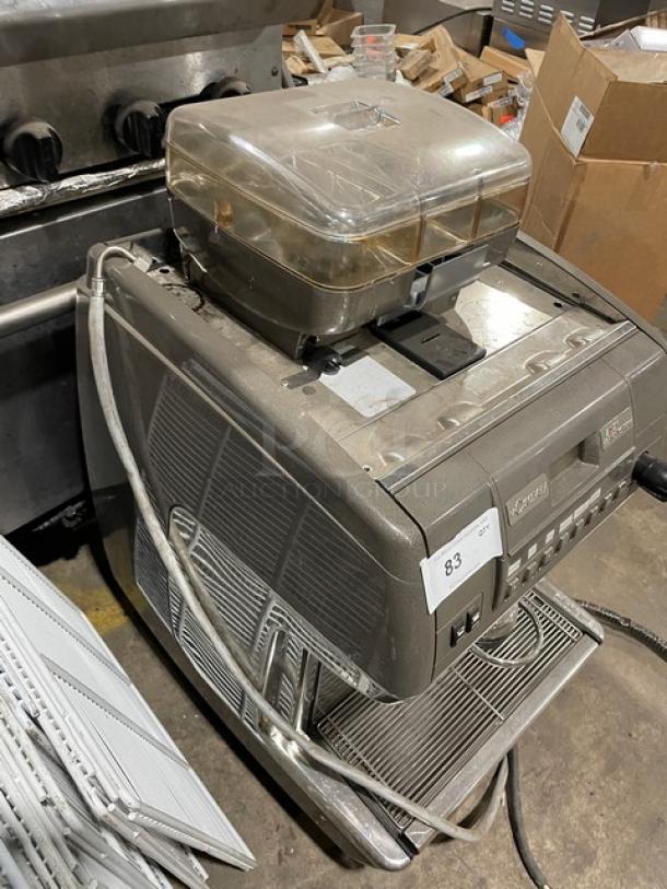 LaCimbali commercial espresso machine with stainless steel steam wand, drip tray, and clear bean hopper. Electric-powered, on legs.