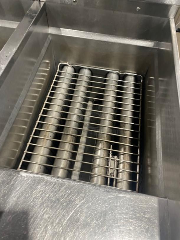 Pitco SSH60 stainless steel natural gas 50 lb. triple-bay deep fat fryer, with backsplash, basket hanger, and casters.