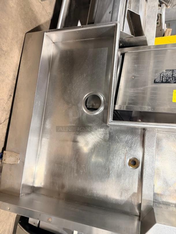 Jackson stainless steel heavy-duty automatic dishwashing machine with L-shaped station and visible drain on legs.