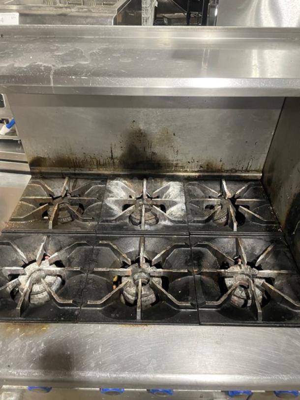 Imperial commercial stainless steel 6-burner range/oven combo, natural gas, with splash guards, salamander shelf, wired oven rack, casters.