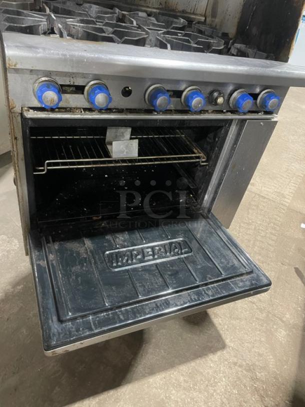 Imperial commercial stainless steel 6-burner gas range/oven combo with splash guards, salamander shelf, and wired rack.