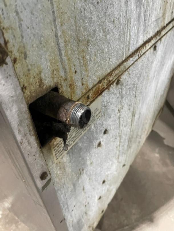 Rust on steel surface of Imperial commercial range. Visible pipe and warning label present. Used condition.