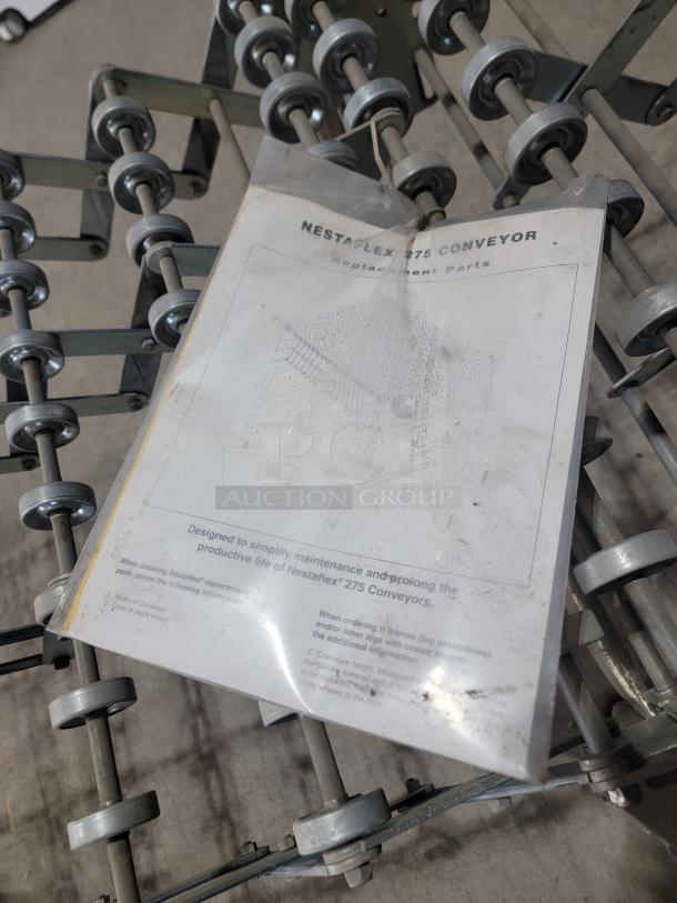 Heavy-duty Nestaflex 275 gravity roller conveyor, all-steel, flexible design with small rollers and locking casters. Visible guide for parts.