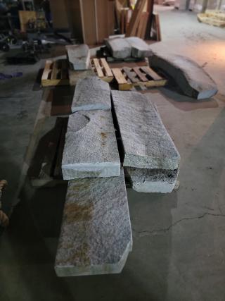 Rustic grey granite slabs on pallets, assorted lengths. Natural texture, ideal for landscaping projects like steps and benches.
