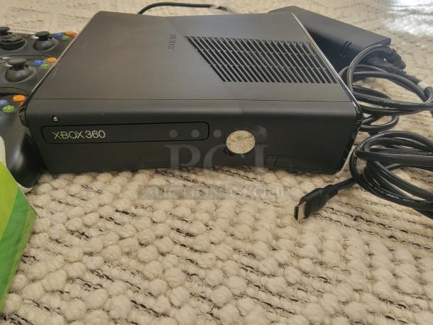 Xbox 360 S console with controller and cables on carpet. Console shows "XBOX 360" label. Ready-to-play bundle.