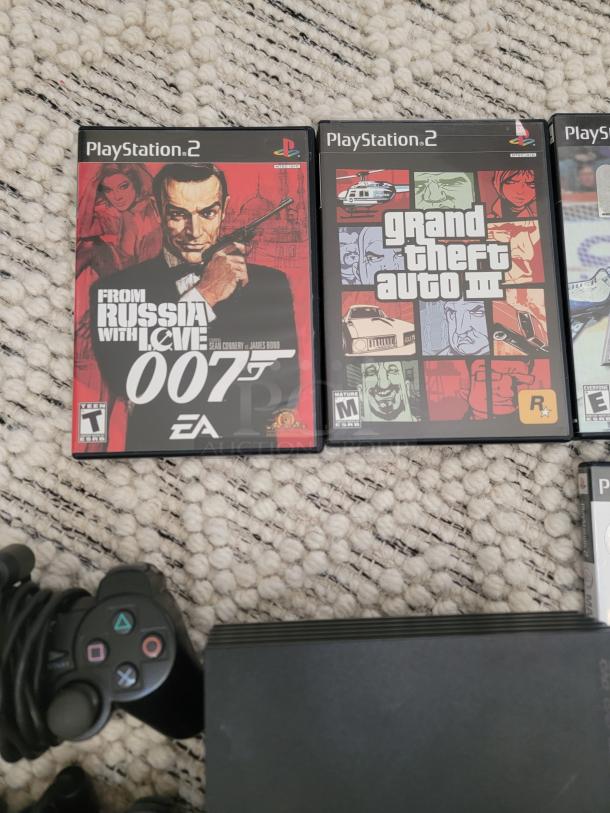 Sony PlayStation 2 console bundle with two controllers and 12 games, including "From Russia with Love" and "Grand Theft Auto III."