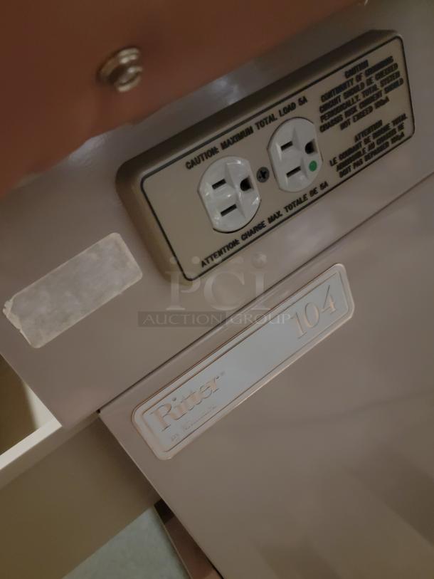 Riter/Brewer 104/Access heavy-duty power table, sturdy design, visible electrical outlets with caution label, ideal for multipurpose use.