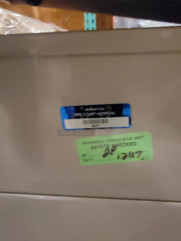 Riter/Brewer 104/Access examination table, beige. Hospital asset and safety checked labels affixed. Versatile heavy-duty design.