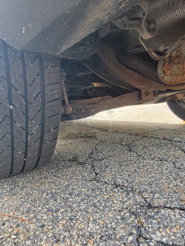 Undercarriage of a 2018 Ford Escape SE 4WD, highlighting tire tread and suspension components. Rust visible on frame.