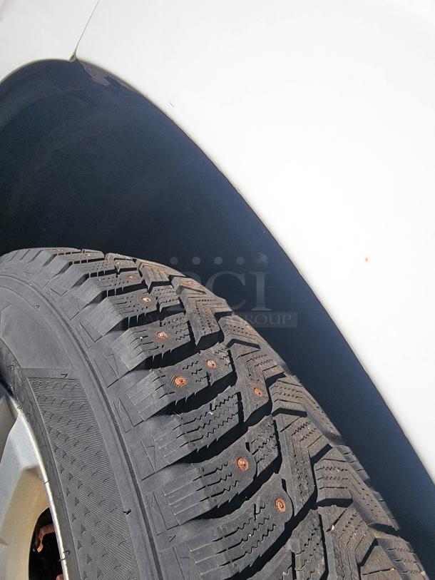 Close-up of a 2015 Chevy Equinox tire and wheel well. The tire shows good tread condition. The vehicle body appears well-maintained.