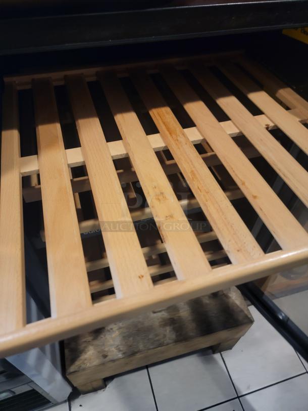 Natural wood sliding shelf inside Eurodib USF-54D wine cooler, designed for cradling bottles.