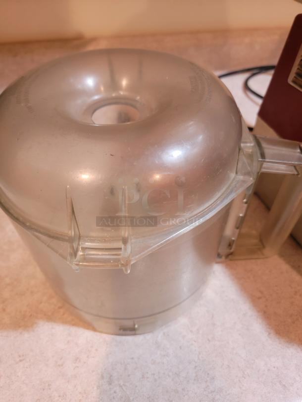 Robot Coupe R2NCLR food processor bowl with top view, highlighting durable, clear plastic construction and secure latch system.