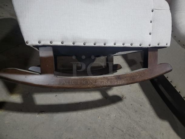 Universal Furniture rocking chair close-up, featuring dark wooden rocker base, upholstered fabric with stud trim detailing.