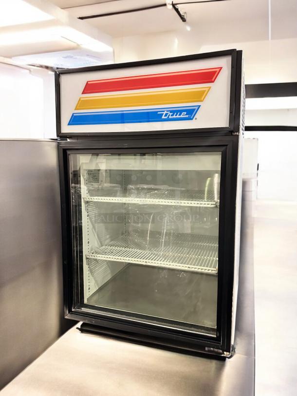 True GDM-05-LD glass door merchandiser refrigerator in superb condition; features clear glass and vibrant signage.