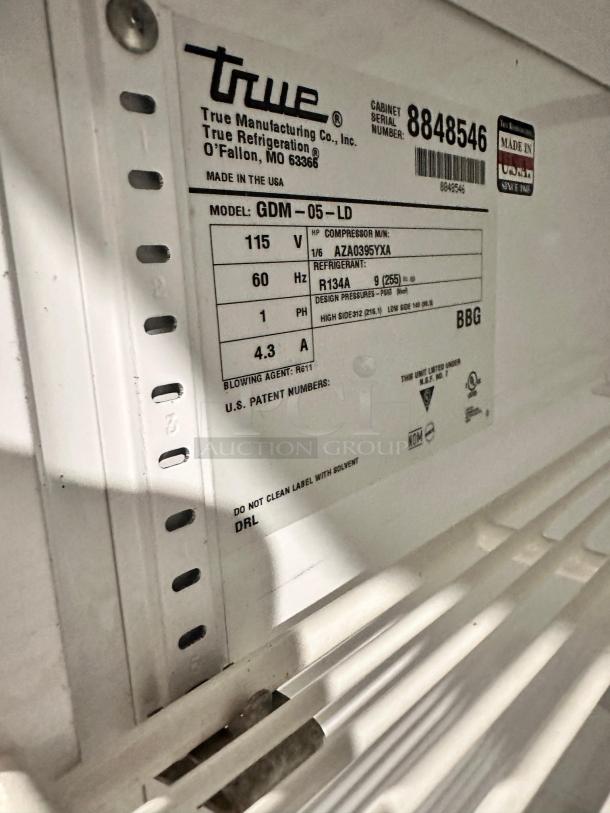 True GDM-05-LD merchandiser label showing model, 115V power, refrigerant R134A, and serial number. Made in USA.