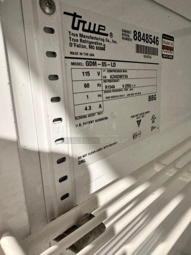 Label on True GDM-05-LD glass door merchandiser, showing model, voltage, refrigerant, and serial number. Made in USA.