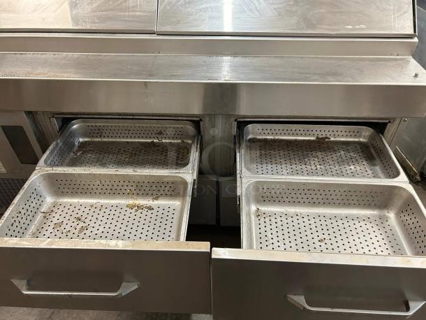 Stainless steel commercial kitchen unit with perforated drawer trays, showing signs of use and wear.