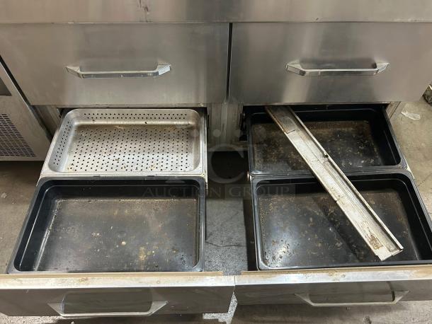 Commercial stainless steel kitchen drawer unit with two open drawers. Visible trays show signs of wear and some rust.