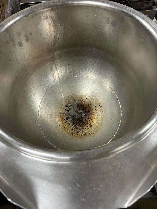 Large stainless steel pot with visible wear and discoloration on the interior. Ideal for kitchen or industrial use.