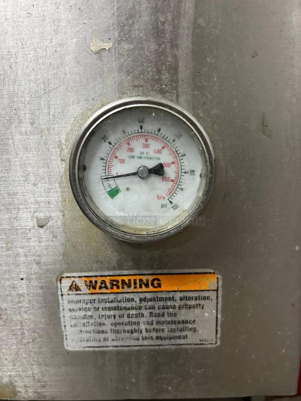 Pressure gauge on metallic surface, showing psi and kPa readings. Warning label advising proper installation and maintenance.
