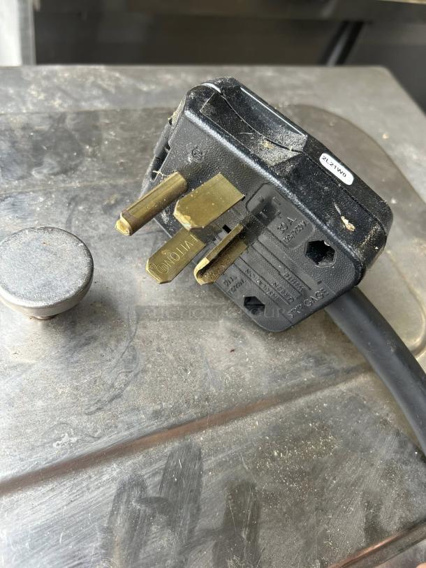 Power plug of a Taylor Model 490 countertop shake freezer, showing prongs and labeling, set on a metal surface.